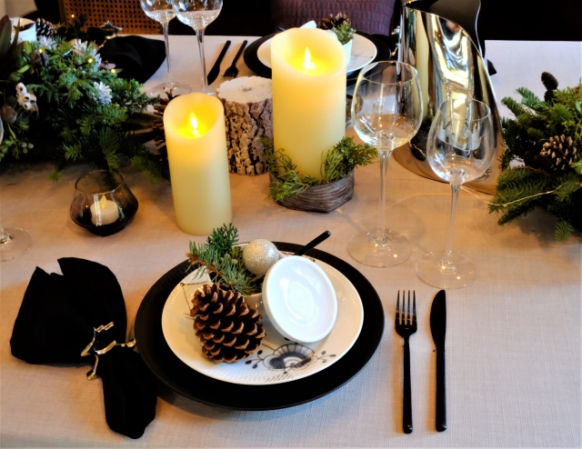 黒のテーブルナプキンと黒のカトラリー、黒のアンダープレートで統一されたクリスマスのテーブル